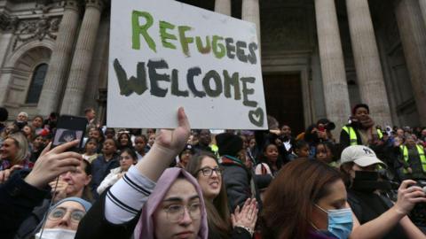 Female campaigners hols up a 'refugees welcome' sign in front of St Paul's Cathedral in London.