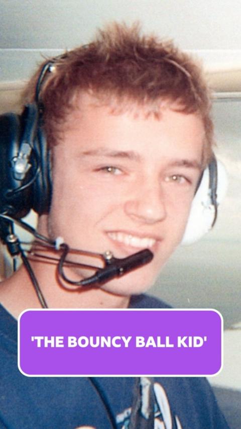 a young man with short brown spiky hair wears a set of headphones while sitting in a plane