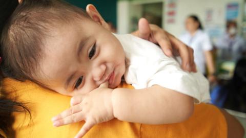 A baby lying on an adult's shoulder in a community centre in Valenzuela City, Manila