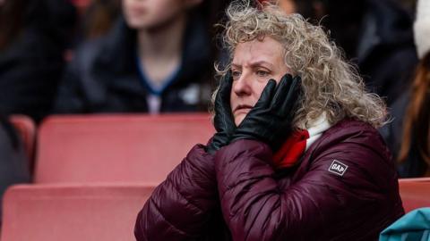 An Arsenal fan cuts a glum figure as she watches on from the stands
