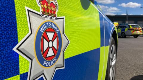 The side of a Wiltshire Police car with yellow and blue livery