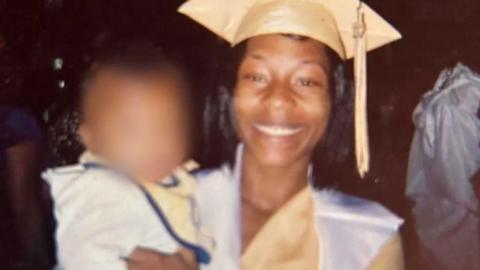 Handout image of Sonya Massey wearing a graduation cap. She carries a child, whose face has been blurred