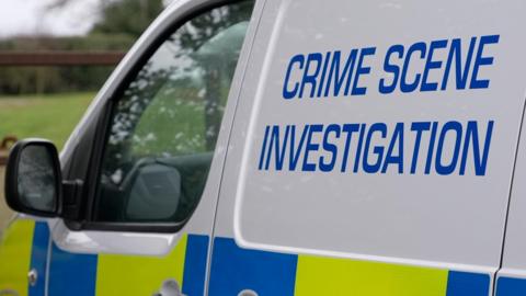 A yellow, white and blue police crime scene investigation van.