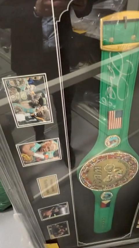 A large belt with a gold detail in the middle, in a big frame with photos.