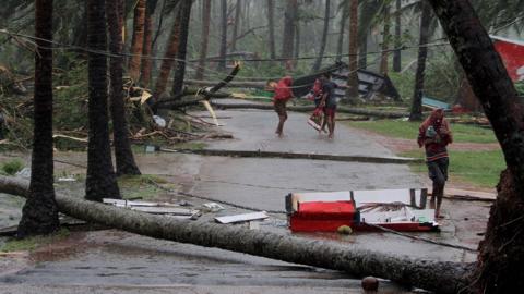 Locals run for shelter between fallen trees after Cyclone Fani made landfall