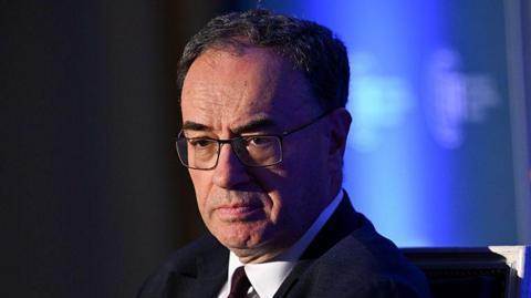 Andrew Bailey head and shoulders wearing a suit and tie with his eyes cast downwards and a serious expression on his face