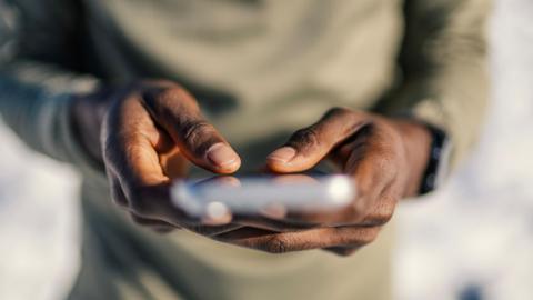 A man using a smart phone. You can only see his hands and his phone