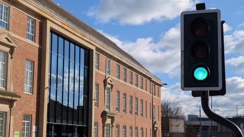 Council building with green light in the foreground and blue, and cloudy skies in the background