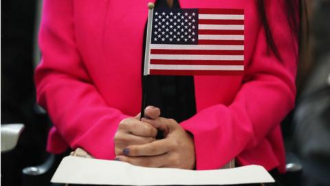 Woman holds flag during naturalisation ceremony