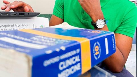 shot of medical books and black man in background