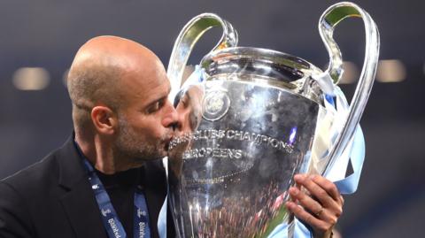 Pep Guardiola, manager of Manchester City, kisses the UEFA Champions League trophy after his team's victory.