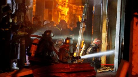 Firefighters work to put out a fire and rescue people at an apartment block in Hanoi on September 13, 2023.