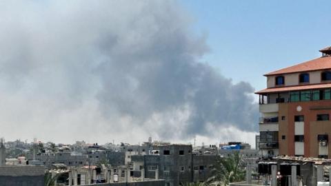 Smoke is seen rising from behind a building in Deir al-Balah