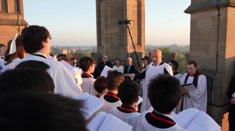 Choristors in white gowns sing from atop Magdalen Tower.