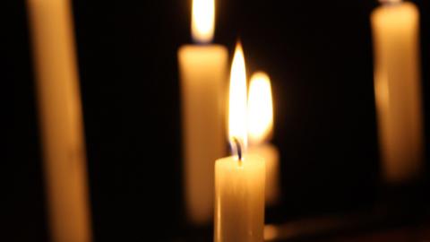 Lit wax candles against a dark background.