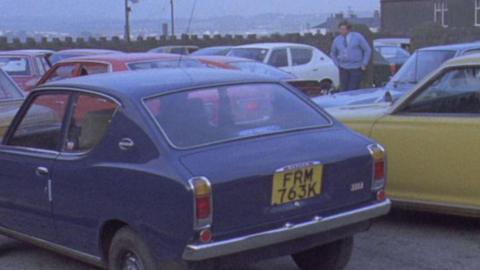 Group of Datsun cars. A man in a blue jumper stands in the background