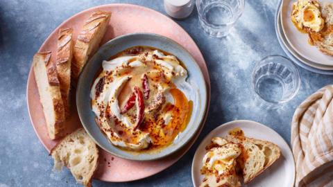 Slices of bread on a pink plate alongside a blue bowl filled with a white and brown butter