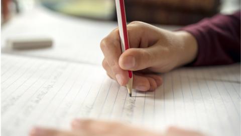 Boy writing in a notepad doing his school work spelling or homework