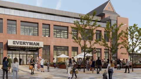 A computer-generated image showing a large two-storey cinema building with an "Everyman" sign over the entrance. There are a lot of people either standing or walking outside the front of the building or sitting down in an outside dining area.