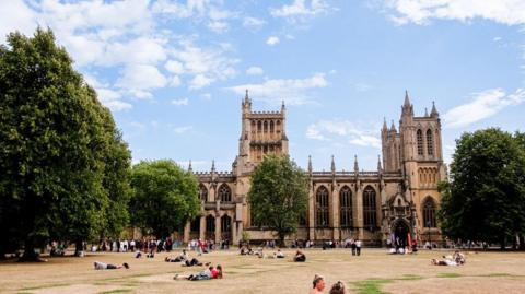 People sitting on yellow grass outside a church.
