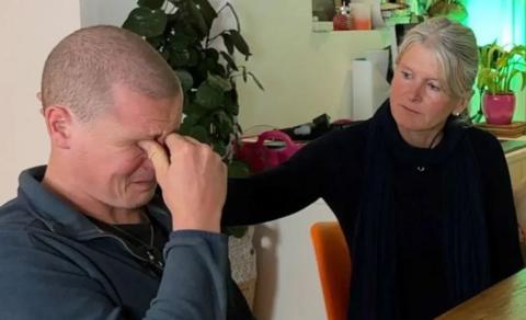 Jamie Morris and his mother Justine listen to the police report into his brother's crash. He is crying with his hand to his face and she has her hand on his shoulder to comfort him