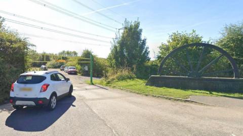An image of a white car driving into the car park entrance of Poolsbrook Country Park in Chesterfield.