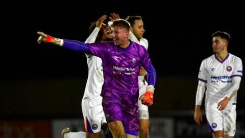 A photo of Mason Terry, in his purple goalkeeping kit for Braintree Town, celebrating a goal against Truro City in the National League Cup in February