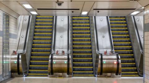 Three escalators in a row, picture taken at the bottom of them 