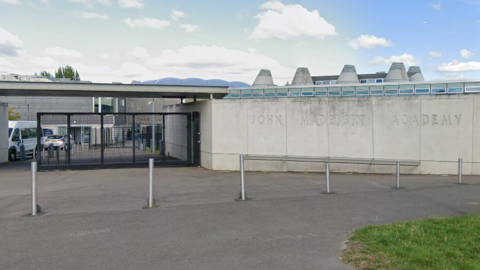 A general view picture of the John Madejski Academy in Reading, which has a stone wall with "John Madesjski Academy" carved into it.
