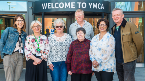 Seven people stand in front of the entrance to the new centre