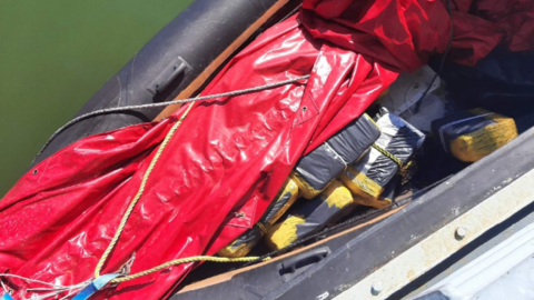 Drugs divided and wrapped as blocks hidden beneath a red tarpaulin in an black inflatable boat. 