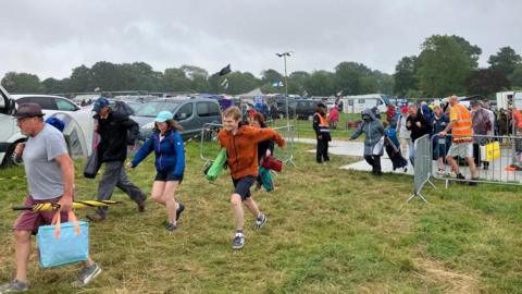 A group of people in coats running across grass.