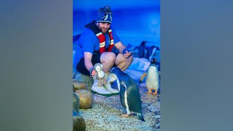 Trainer showing Daley the Penguin a knitted toy