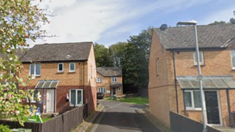 A screengrab from Google streetview of a dead-end residential street surrounded by brick houses. 