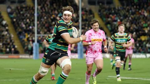 Alex Coles, wearing the gold, green and black of Northampton Saints, breaks through to go on and score against Harlequins.