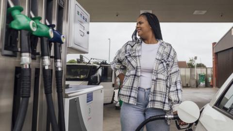 Woman using a petrol pump in the North East of England