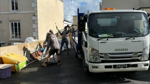 Three of the employees at JLC Paving removing the fly-tipped waste outside the boxing club to their van. 