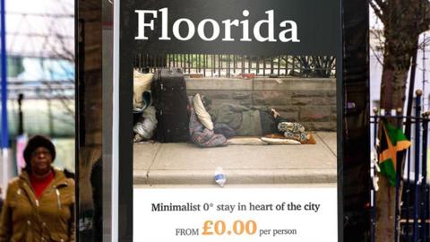 An advertising campaign shows a billboard with the slogan "Floorida". The poster has an image of someone sleeping on the ground, on a pavement, and reads "minimalist 0* stay in heart of the city". It has a made-up company name called Street Escapes.
