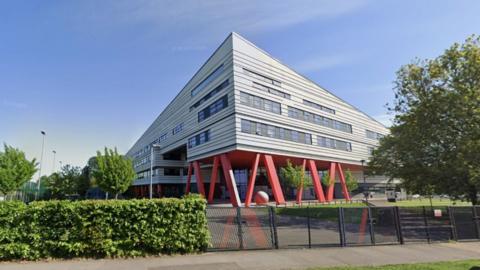 Exterior of Marvell College. A modern triangular building with red supporting pillars.