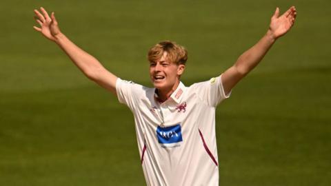 Alfie Ogborne holds his arms in the air in celebration on the field