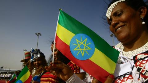 Ethiopians hold their national flag as they wait to meet the Ethiopian prime minister on May 2, 2018.