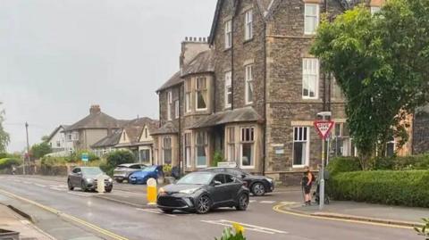 Image of a junction in Ambeside, Cumbria. A grey car is exiting the junction and turning the wrong way onto a one-way street.