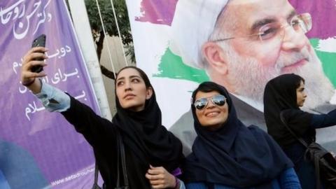 Women pose in front of posters of Hassan Rouhani in Tehran (09/05/17)