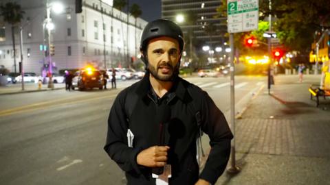 BBC correspondent Carl Nasman wearing a helmet on a street at night in LA