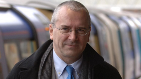 Peter Hendy stands by a tube train  