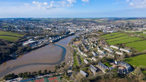 A image taken from above of part of Truro. Including in the picture is a long stretch of river, numerous buildings and the centre of Truro in the distance.