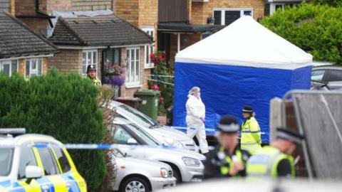 Police at the scene of the attack - police cars and tape in the foreground, with a forensics tent in the background