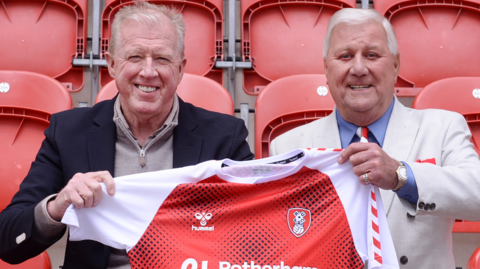 Steve McClaren is holding a red Rotherham United shirt alongside Tony Stewart.