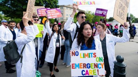 People in white jackets hold signs