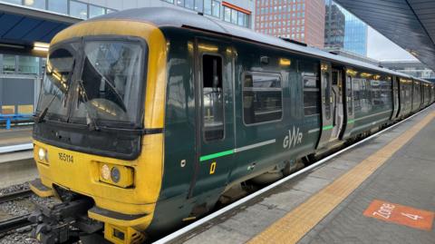 A dark green Great Western Railway train at a station.